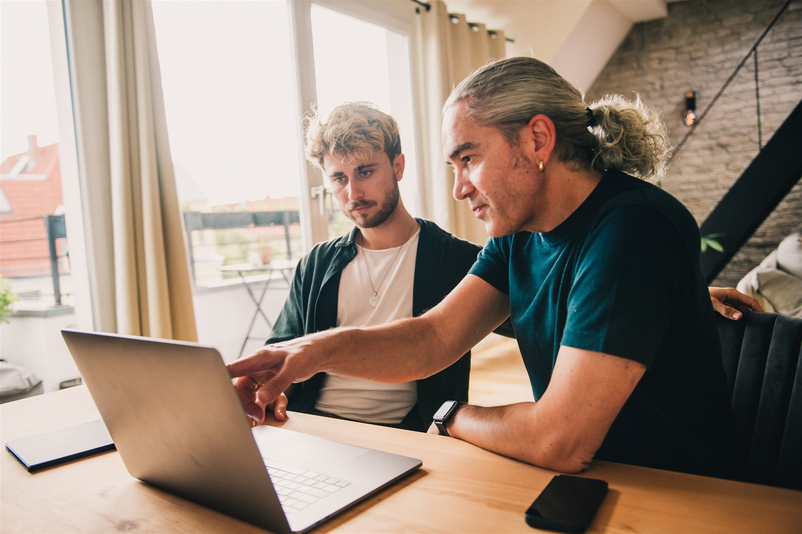 Zwei Männer sitzen vor einem Laptop und besprechen die Verwaltung des digitalen Nachlasses.